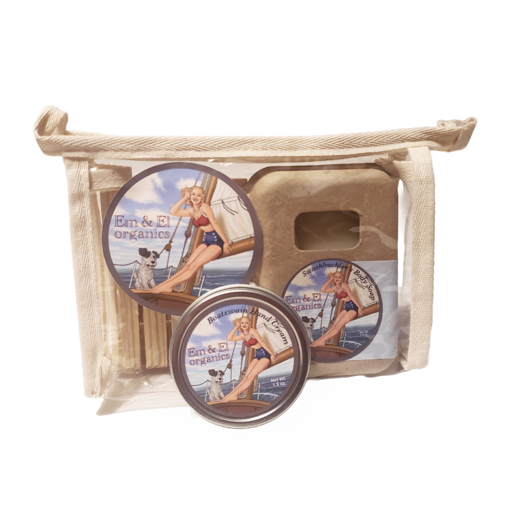 A transparent travel toiletry bag with a wooden soap dish, a tin of Boatswain Hand Cream, and a boxed bar of Swashbuckler's Body Soap on a white background